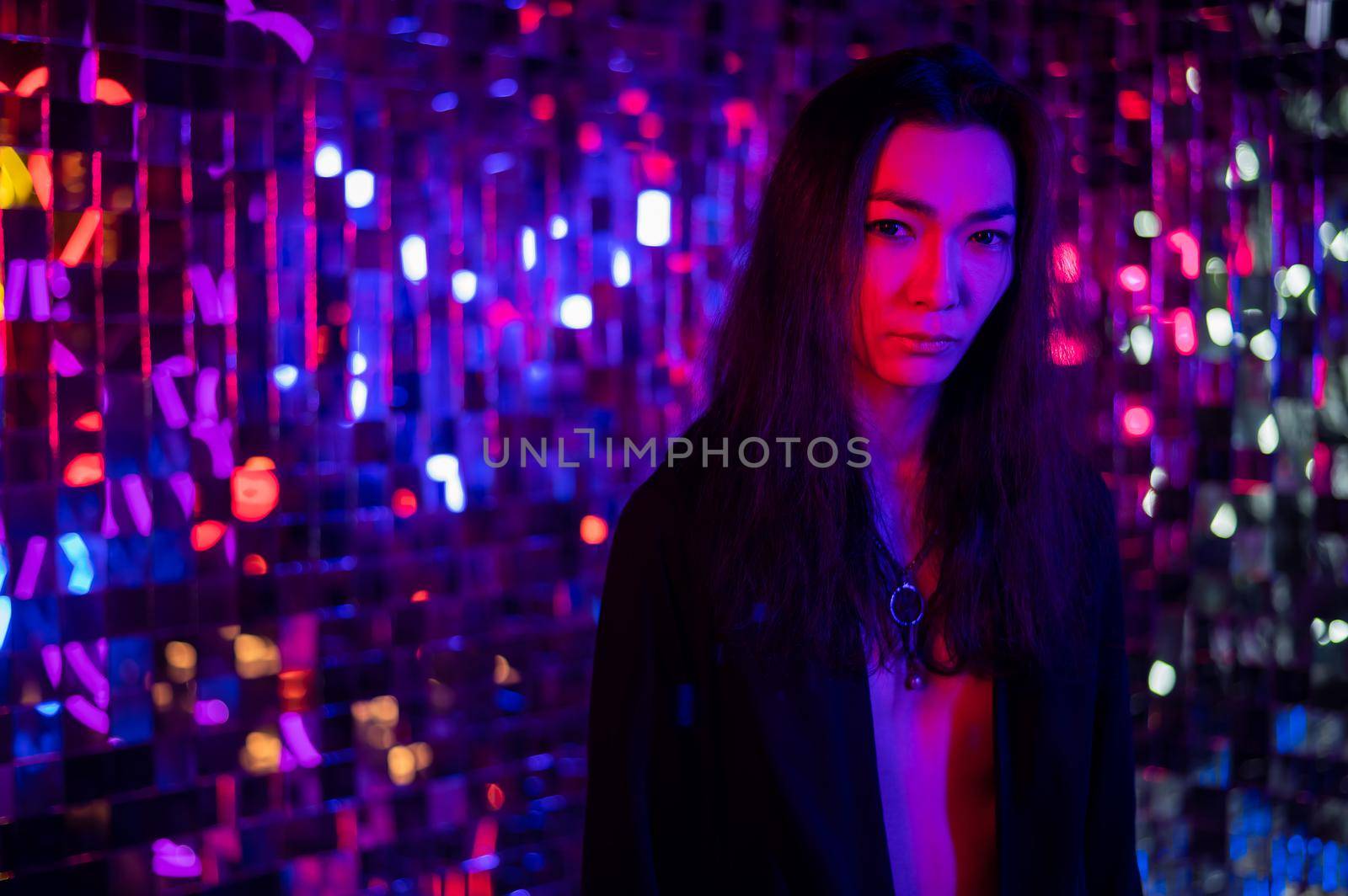Close-up portrait of an androgenic model. Male transgender in studio with neon light