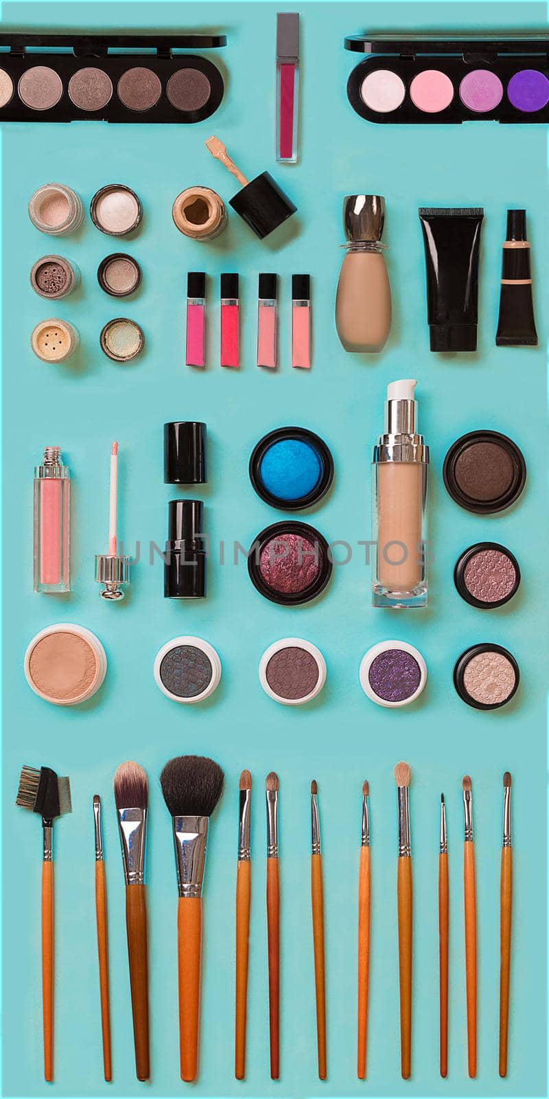 cosmetics for facial makeup: brushes, powder, lipstick, eye shadow, trimmer and other accessories on blue background top view. Beauty flat lay concept