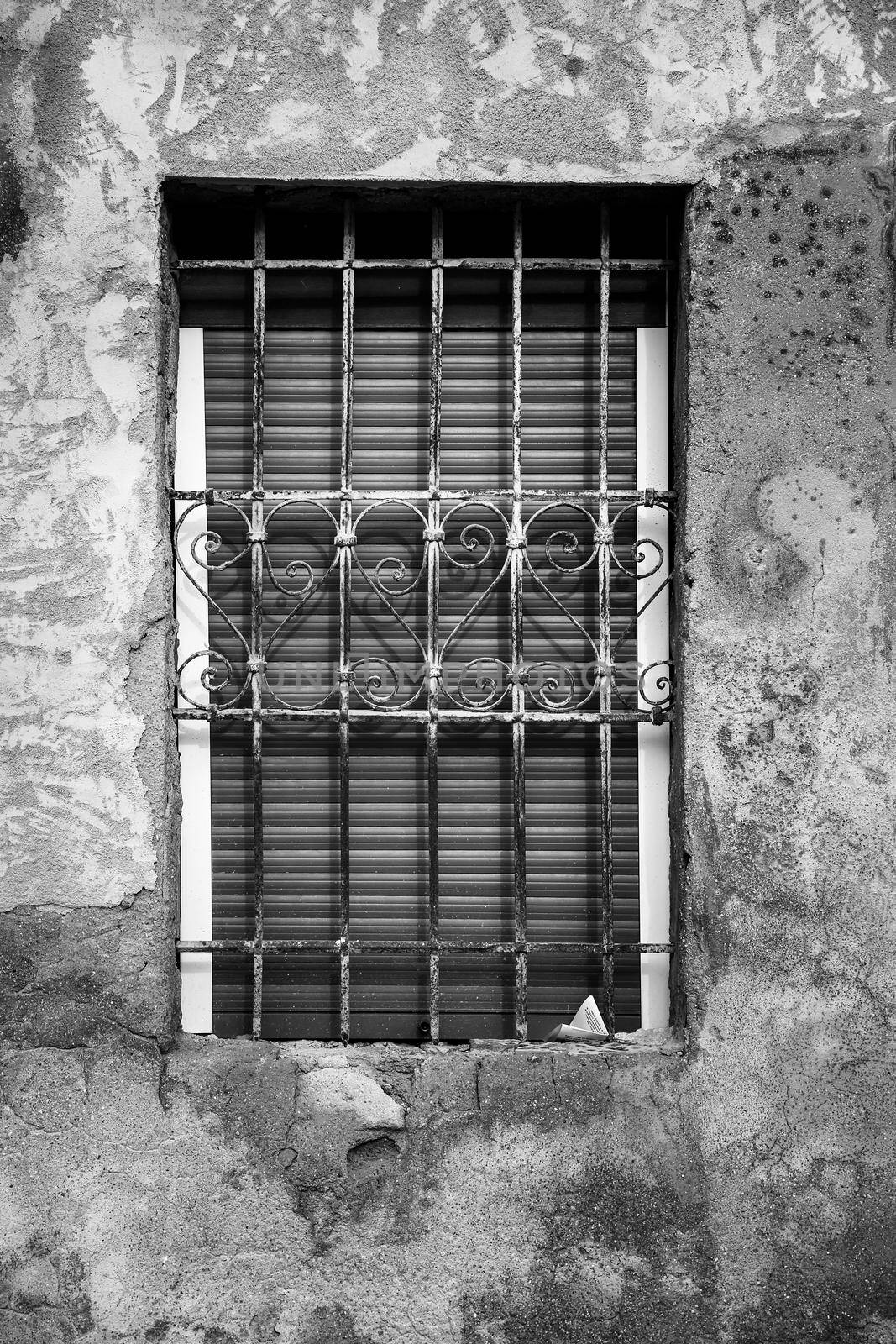 Window with forged metal lattice with curved details and wooden blind