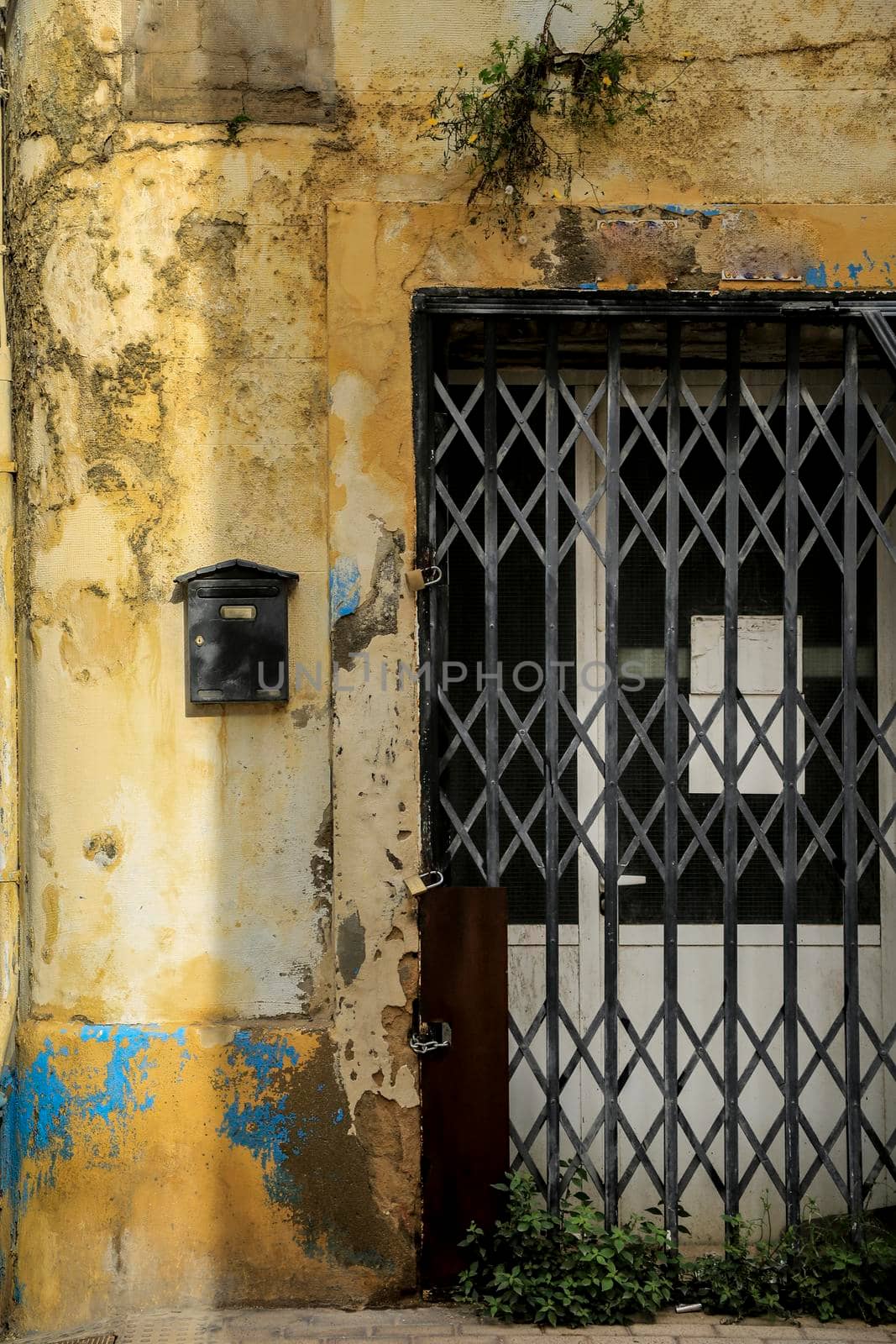 Black mailbox on chipped facade next to door by soniabonet