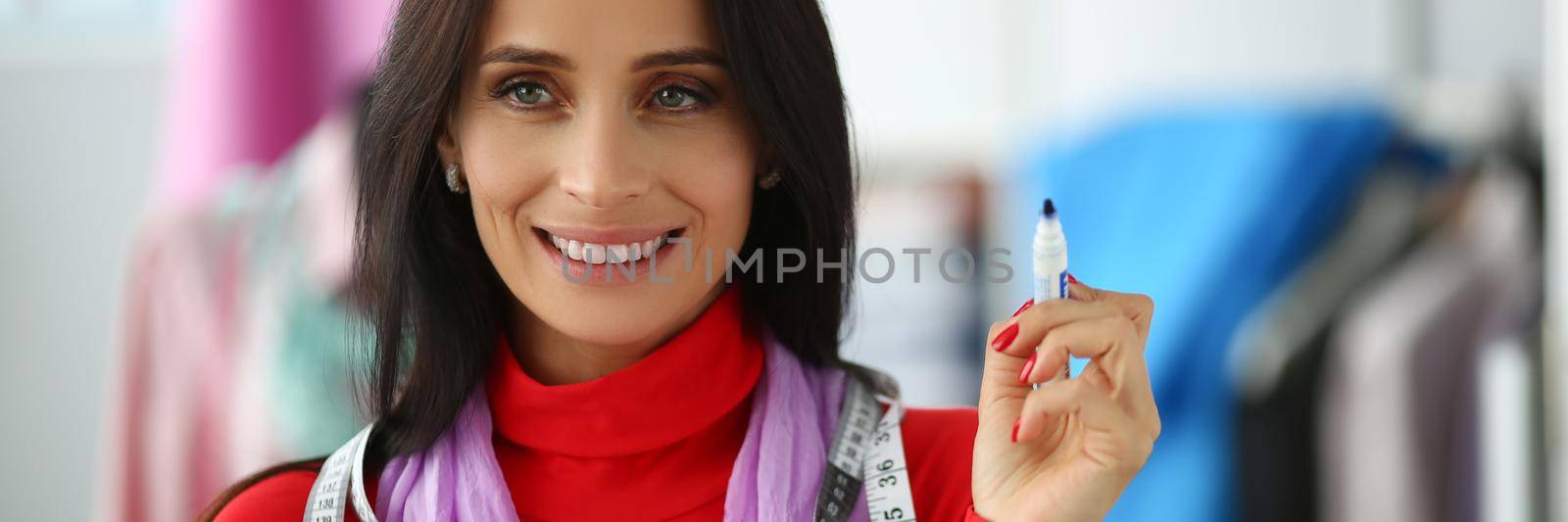 Portrait of young woman stylist designer with marker in hand. Fashion designer profession concept