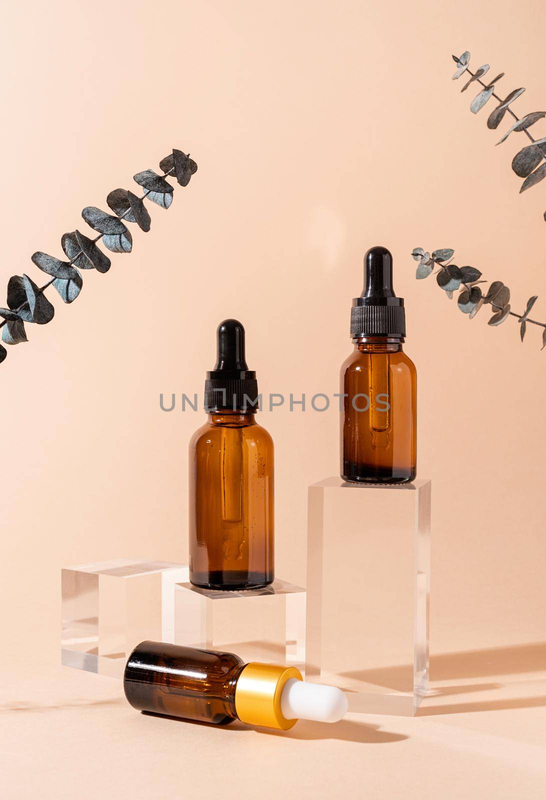 Glass dropper bottles with a pippette with black rubber tip on glass podium and beige background. Nature Skin concept. Organic Spa Cosmetics. Trendy concept.