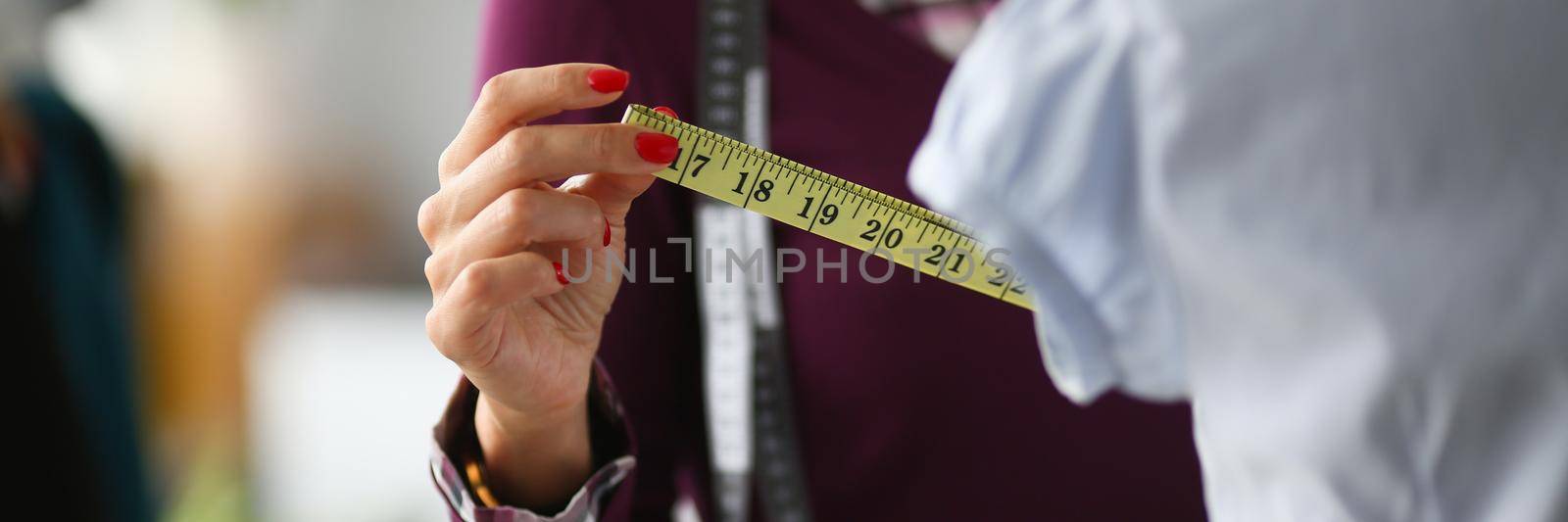 Woman fashion designer takes measurements with centimeter by kuprevich