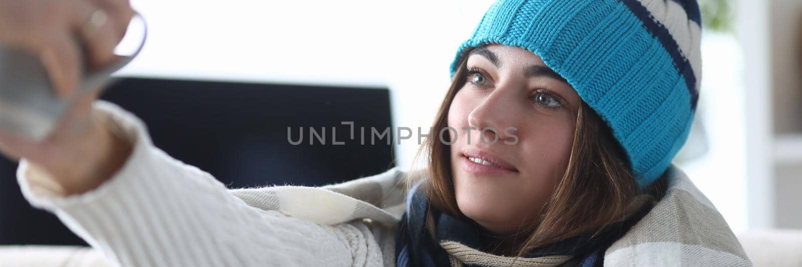 Young woman in hat and plaid with chills takes cup of medicine. Antipyretic drugs at home concept