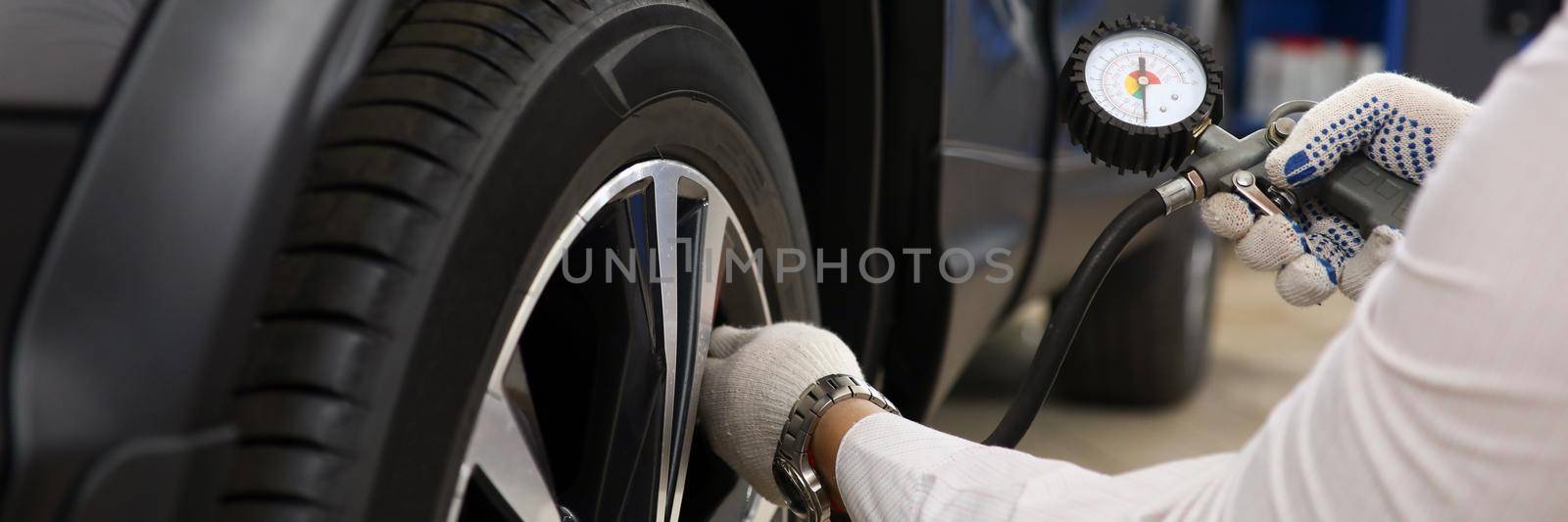 Technician checks tire pressure of car. Tire service concept