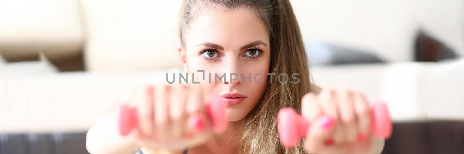 Beautiful young woman doing exercises with dumbbells by kuprevich