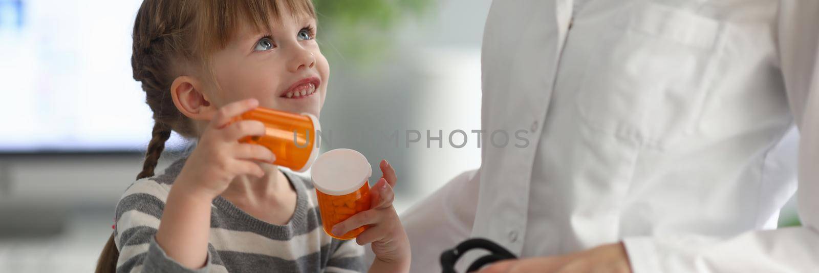 Little girl holding pills at pediatrician appointment. Medicine for small children concept