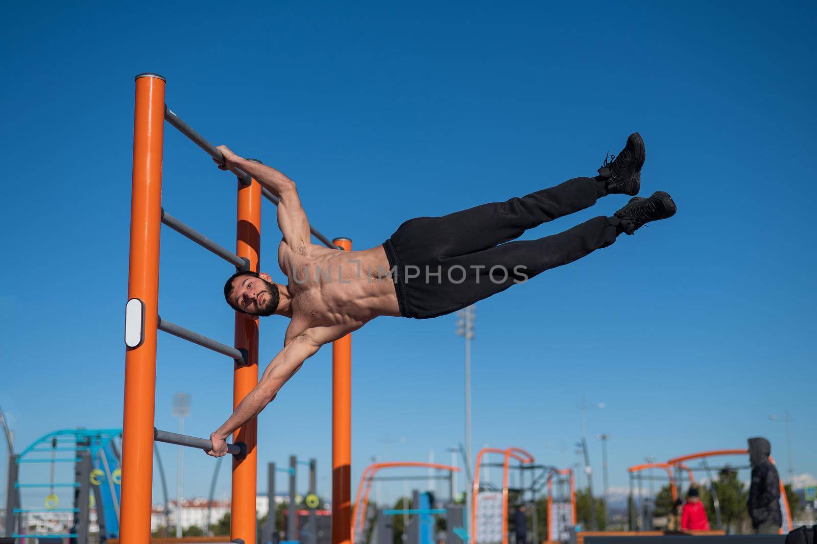 Shirtless man doing human flag outdoors. by mrwed54