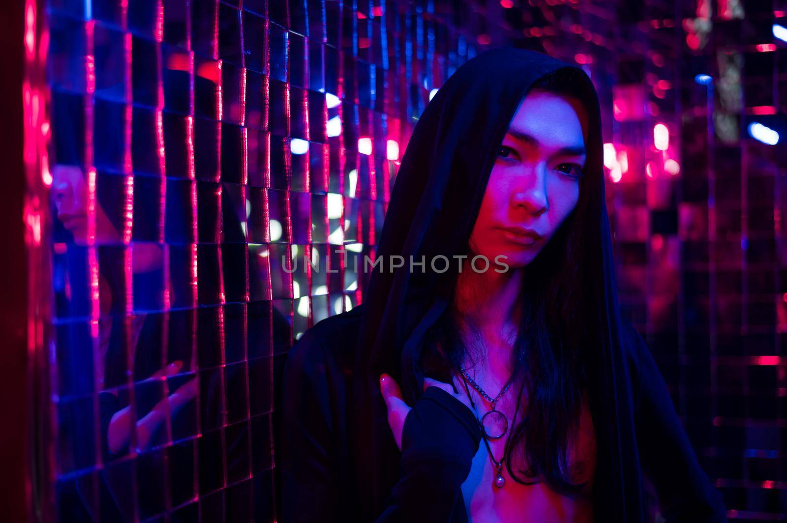 Close-up portrait of an androgenic model in a hood. Male transgender in studio with neon light. by mrwed54