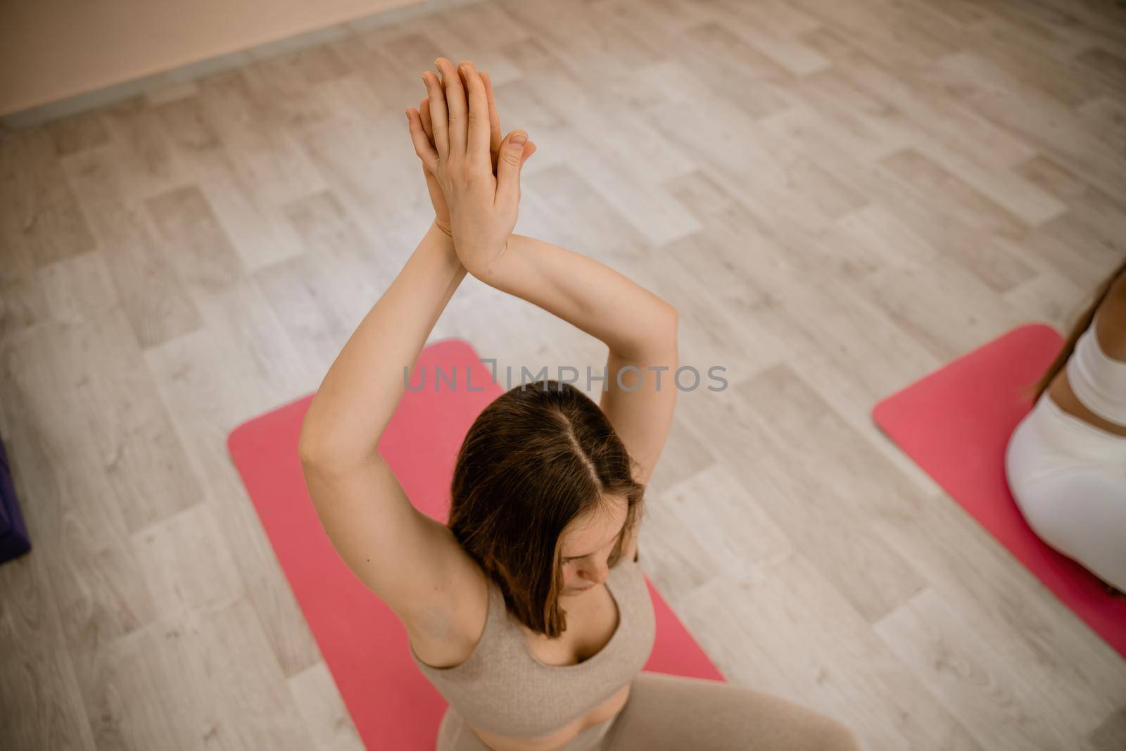 Girl does yoga. Young woman practices asanas on a beige one-ton background