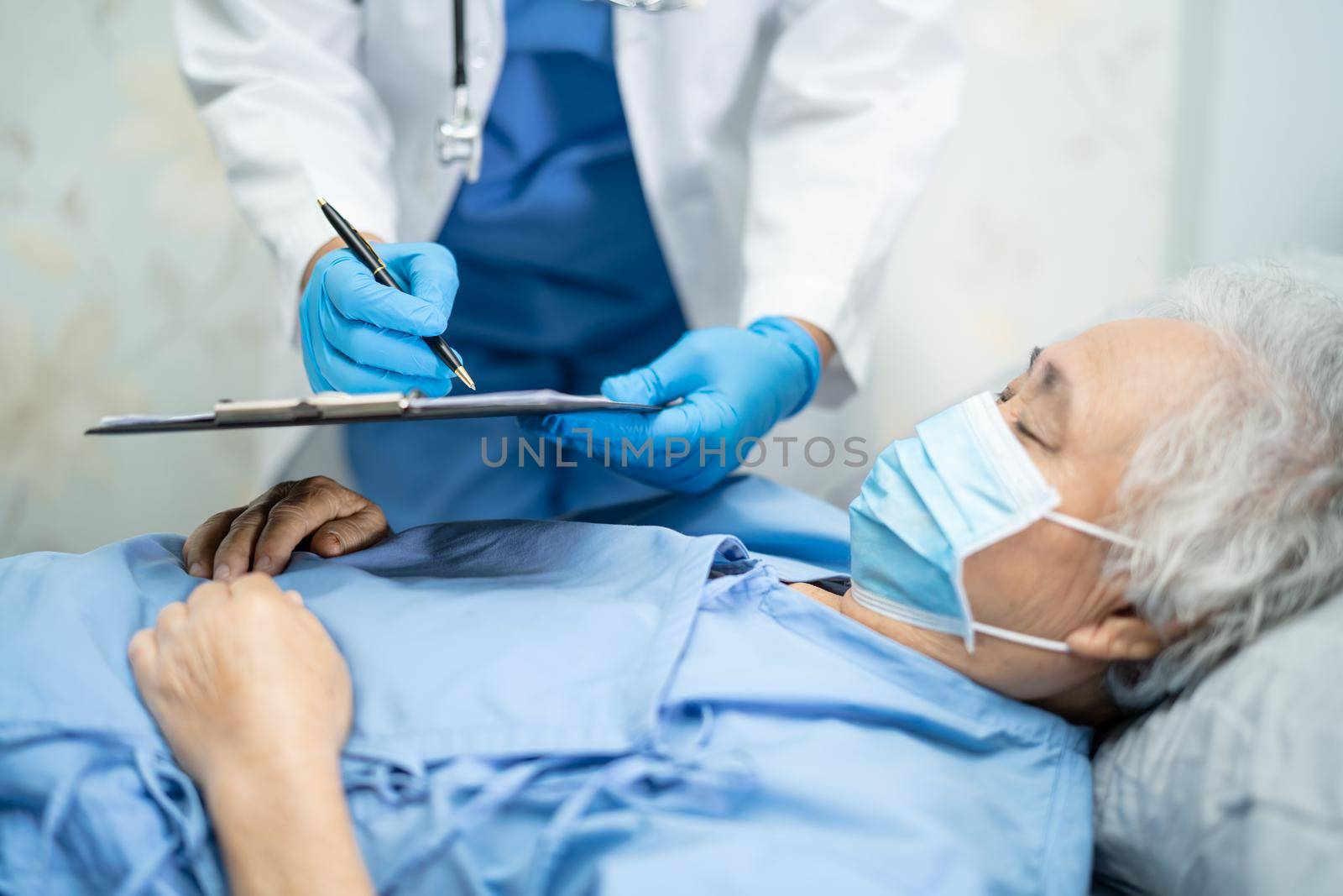 Doctor using stethoscope to checking Asian senior or elderly old lady woman patient wearing a face mask in hospital for protect infection Covid-19 Coronavirus.