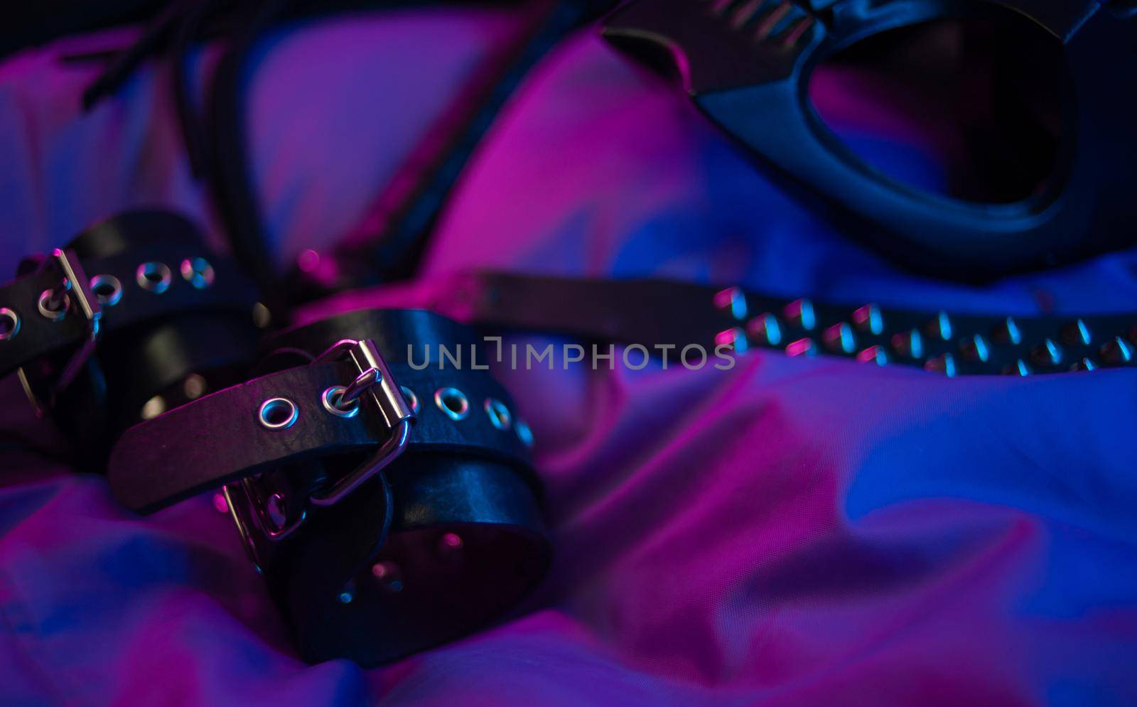 leather bdsm handcuffs and accessories for bdsm games in neon light by Rotozey