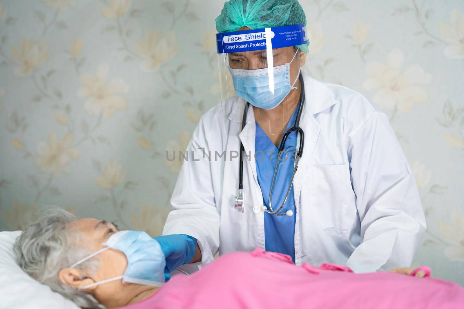 Asian doctor wearing face shield and PPE suit new normal to check patient protect safety infection Covid-19 Coronavirus outbreak at quarantine nursing hospital ward.