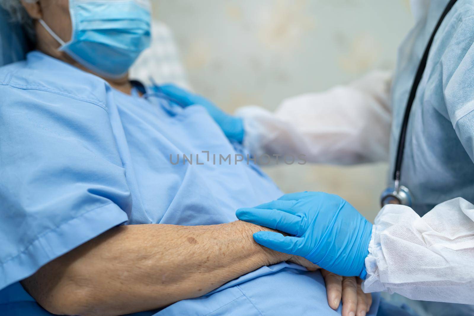 Doctor using stethoscope to checking Asian senior or elderly old lady woman patient wearing a face mask in hospital for protect infection Covid-19 Coronavirus. by pamai