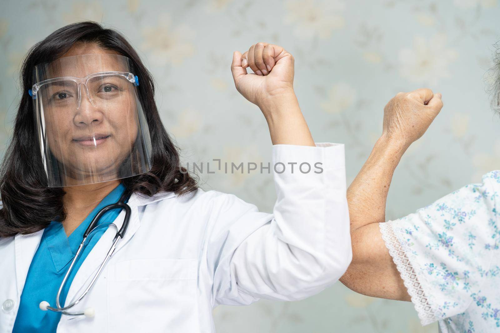 Asian doctor and elder patient bump elbows for new normal to social distancing avoid covid-19 coronavirus. by pamai