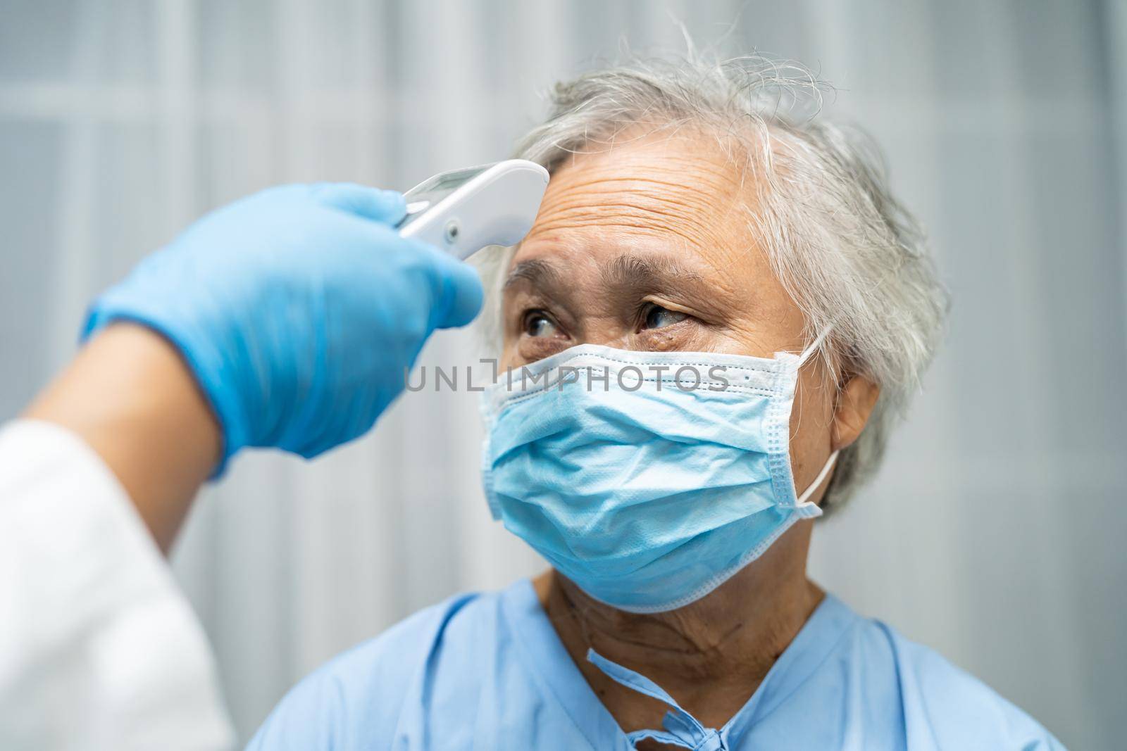 Doctor holding digital thermometer to measures asian senior or elderly old lady woman patient wearing a face mask have a fever in hospital, healthy strong medical concept.