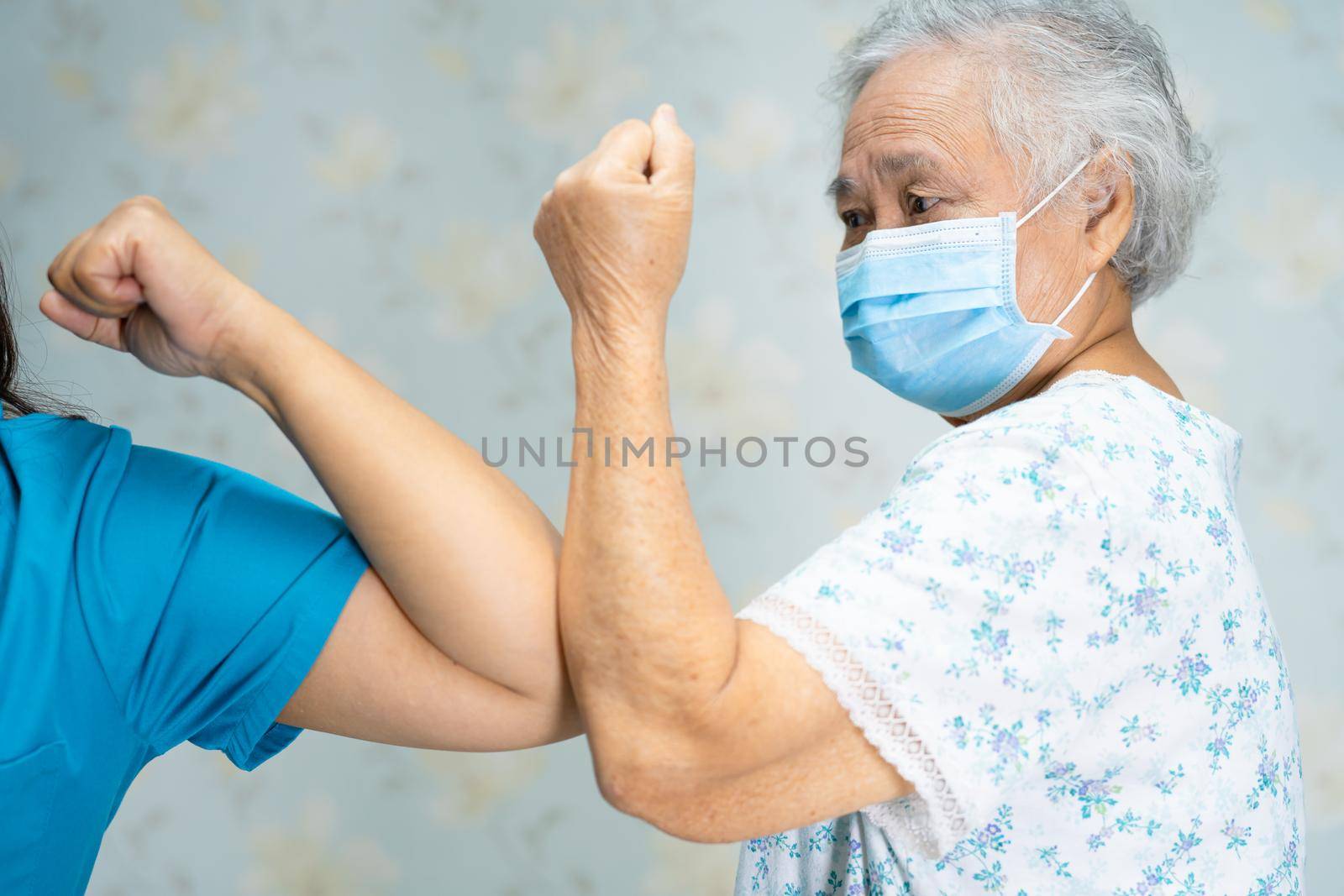 Asian doctor and elder patient bump elbows for new normal to social distancing avoid covid-19 coronavirus.