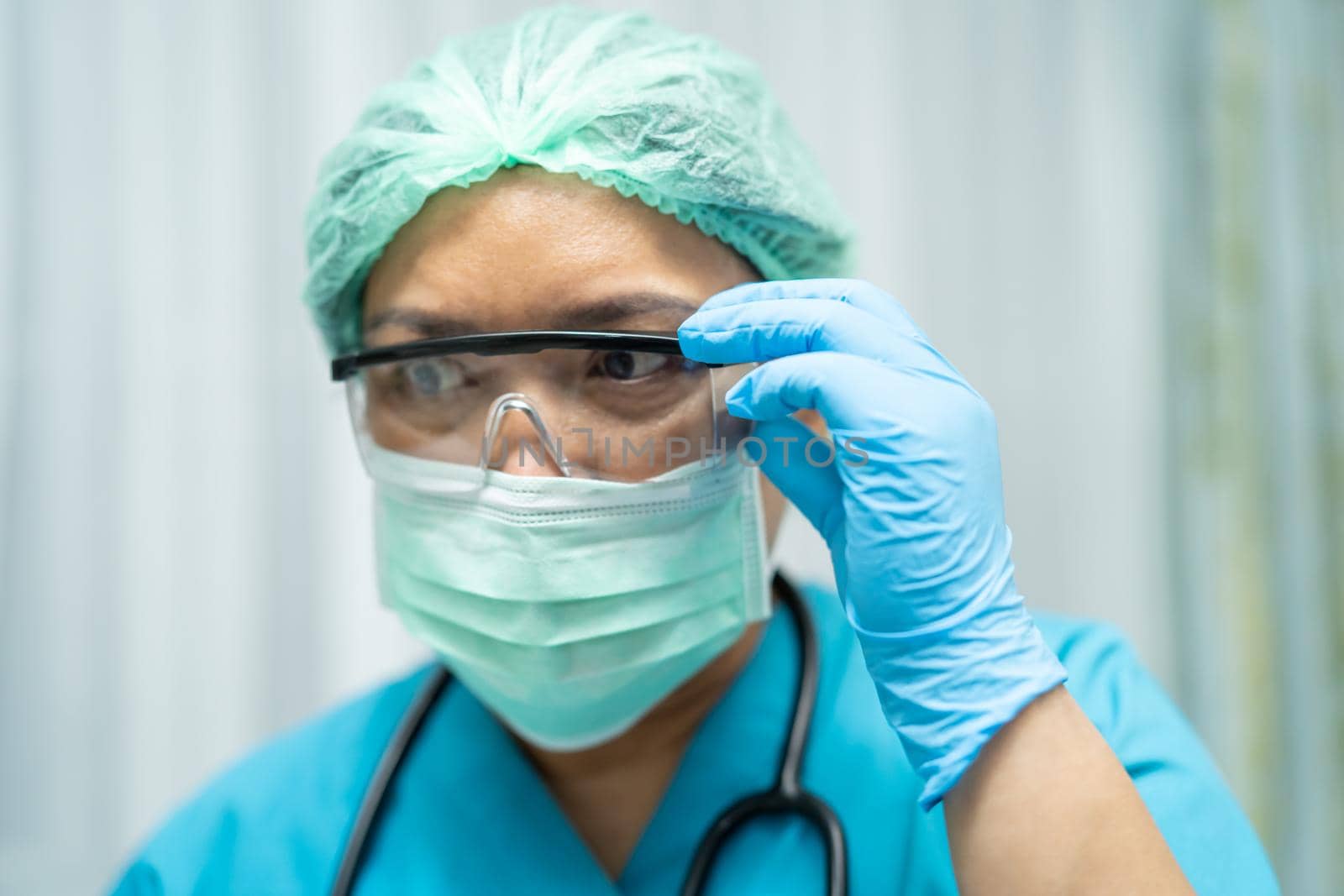 Asian doctor wearing face shield and PPE suit new normal to check patient protect safety infection Covid-19 Coronavirus outbreak at quarantine nursing hospital ward.