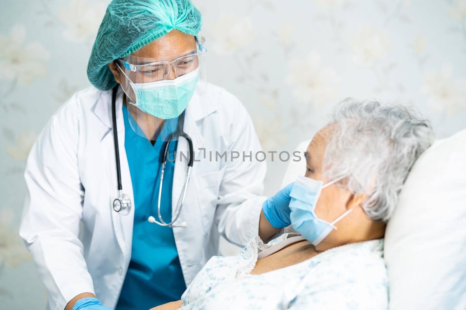 Asian doctor wearing face shield and PPE suit new normal to check patient protect safety infection Covid-19 Coronavirus outbreak at quarantine nursing hospital ward.