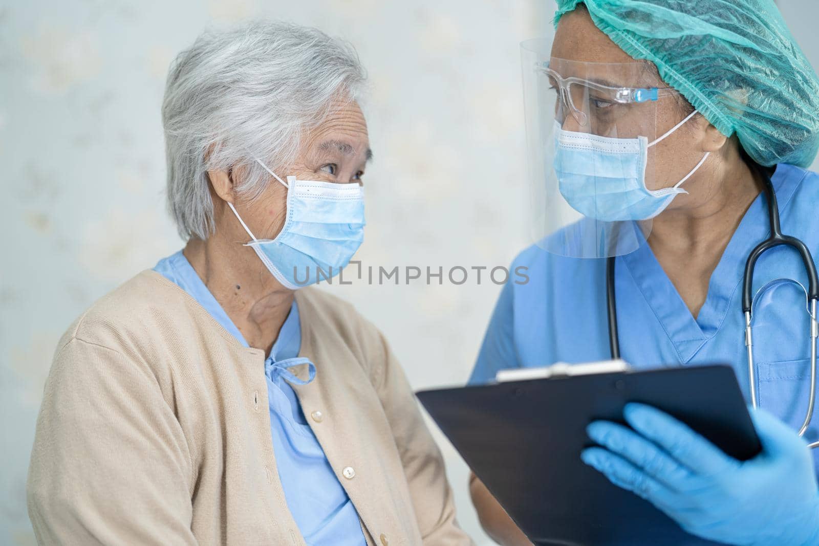 Asian doctor wearing face shield and PPE suit new normal to check patient protect safety infection Covid-19 Coronavirus outbreak at quarantine nursing hospital ward.