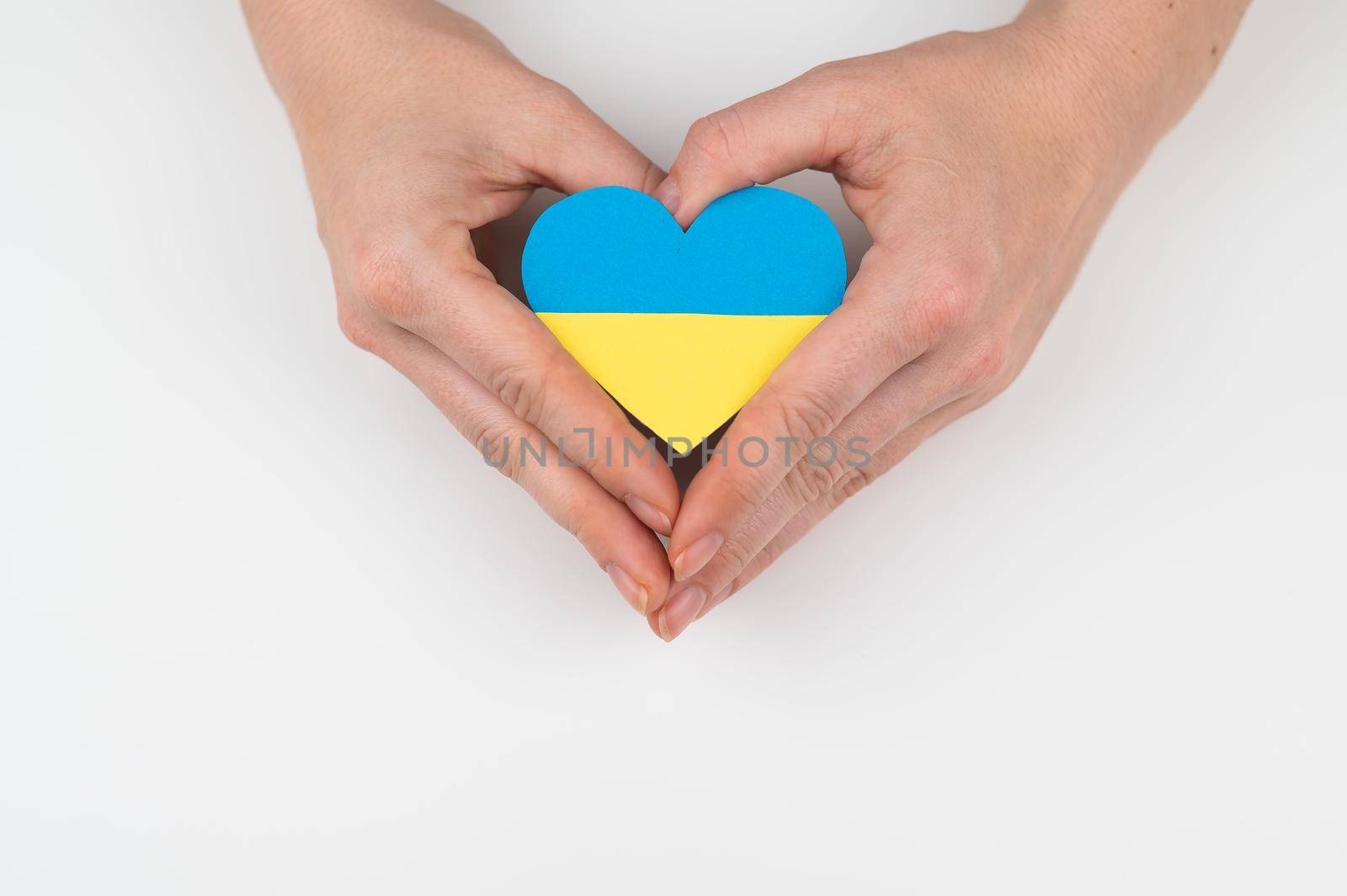 A woman holds a heart with the flag of Ukraine on a white background