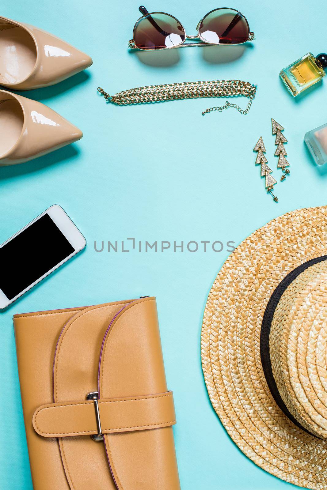 Flat lay, top view, mock up women's clothes and accessories on a turquoise background. Telephone, sunglasses, bracelet, straw