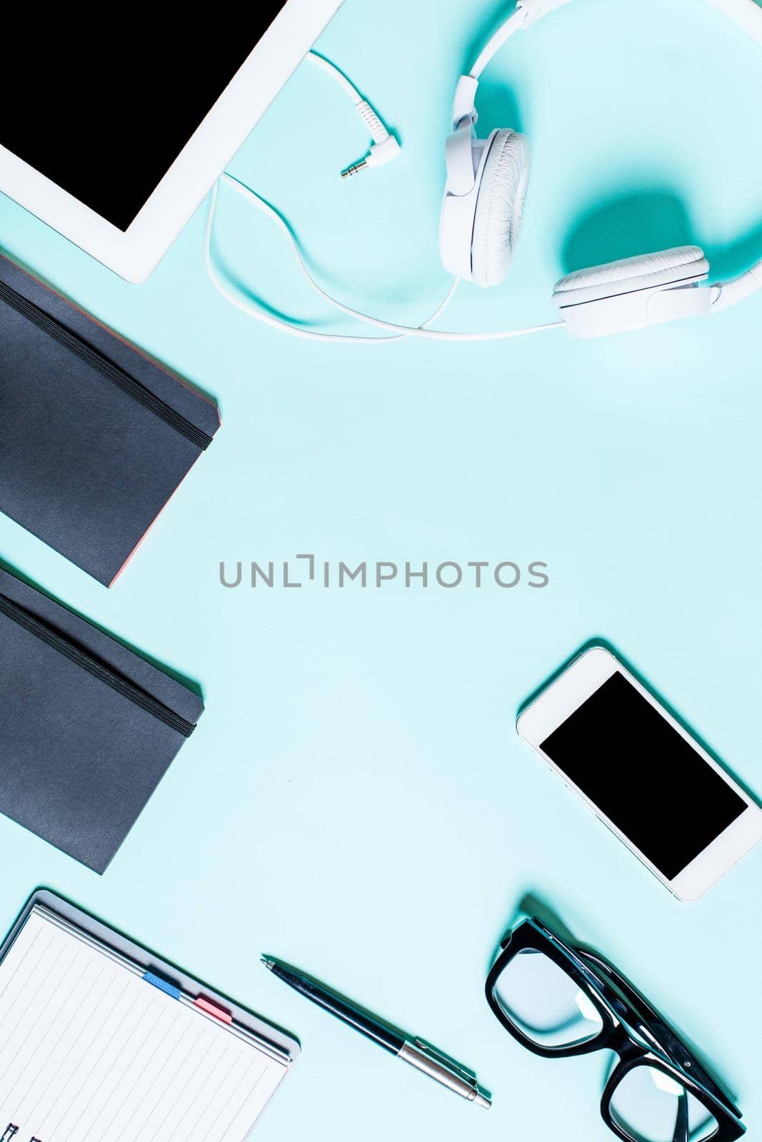 Working place with tablet, smartphone and glasses on a turquoise background by nazarovsergey