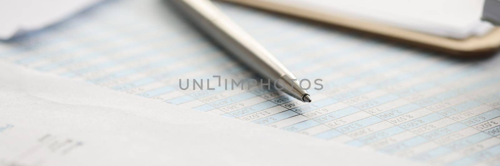 Metal ballpoint pen lying on documents with numbers closeup. Statistics and accounting concept