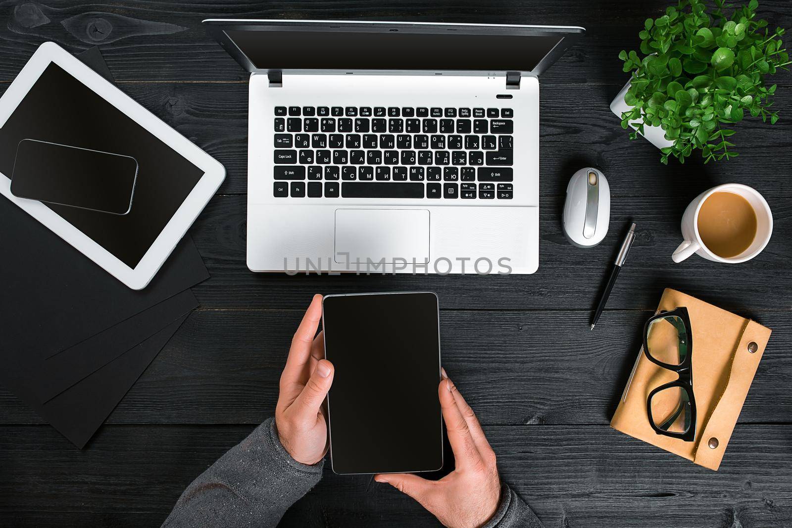 Hipster black wooden desktop top view, male hands typing on a laptop. Top view. Copy space