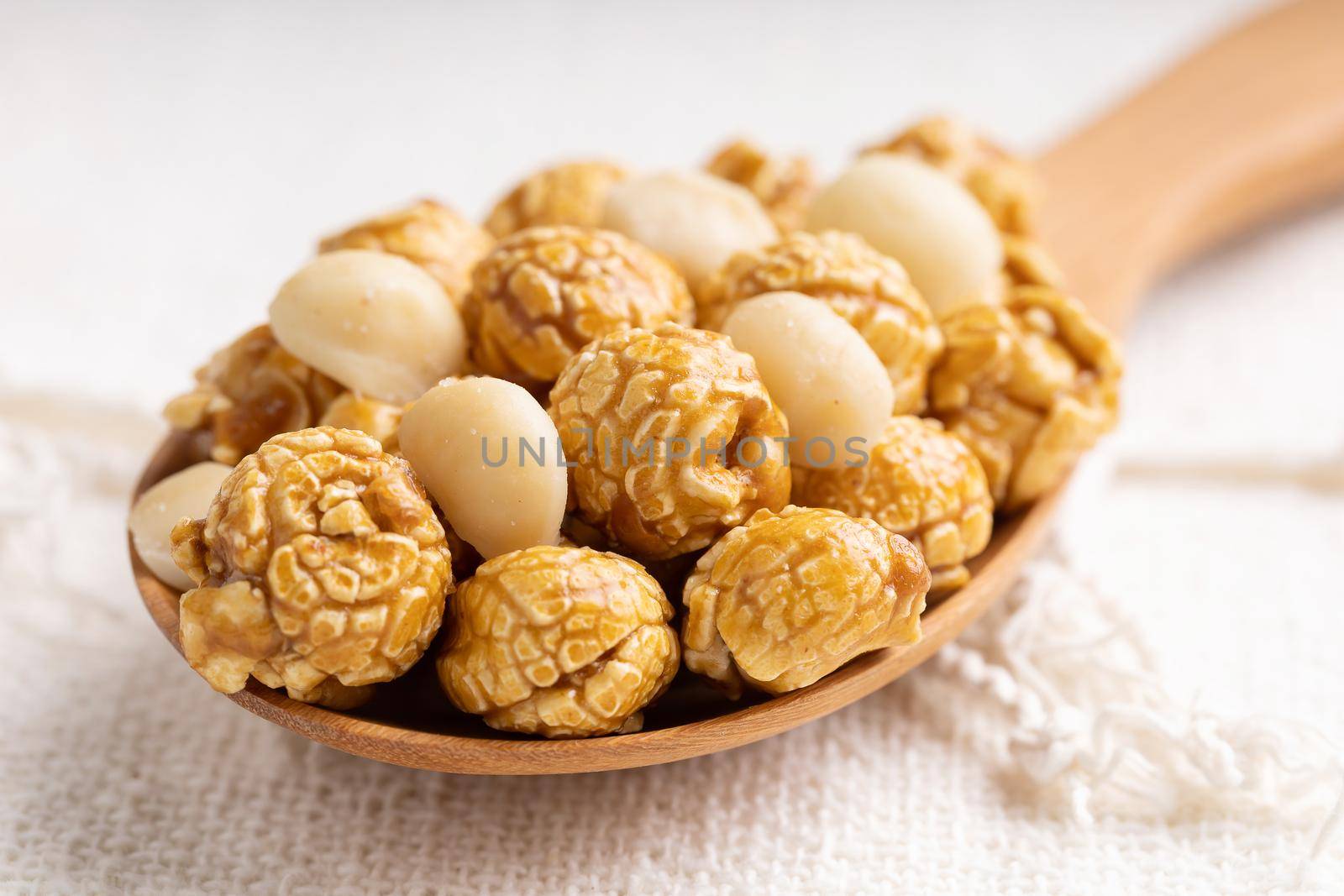 Golden color caramel popcorn with macadamia nut in wooden ladle, Crunchy and sweet dessert