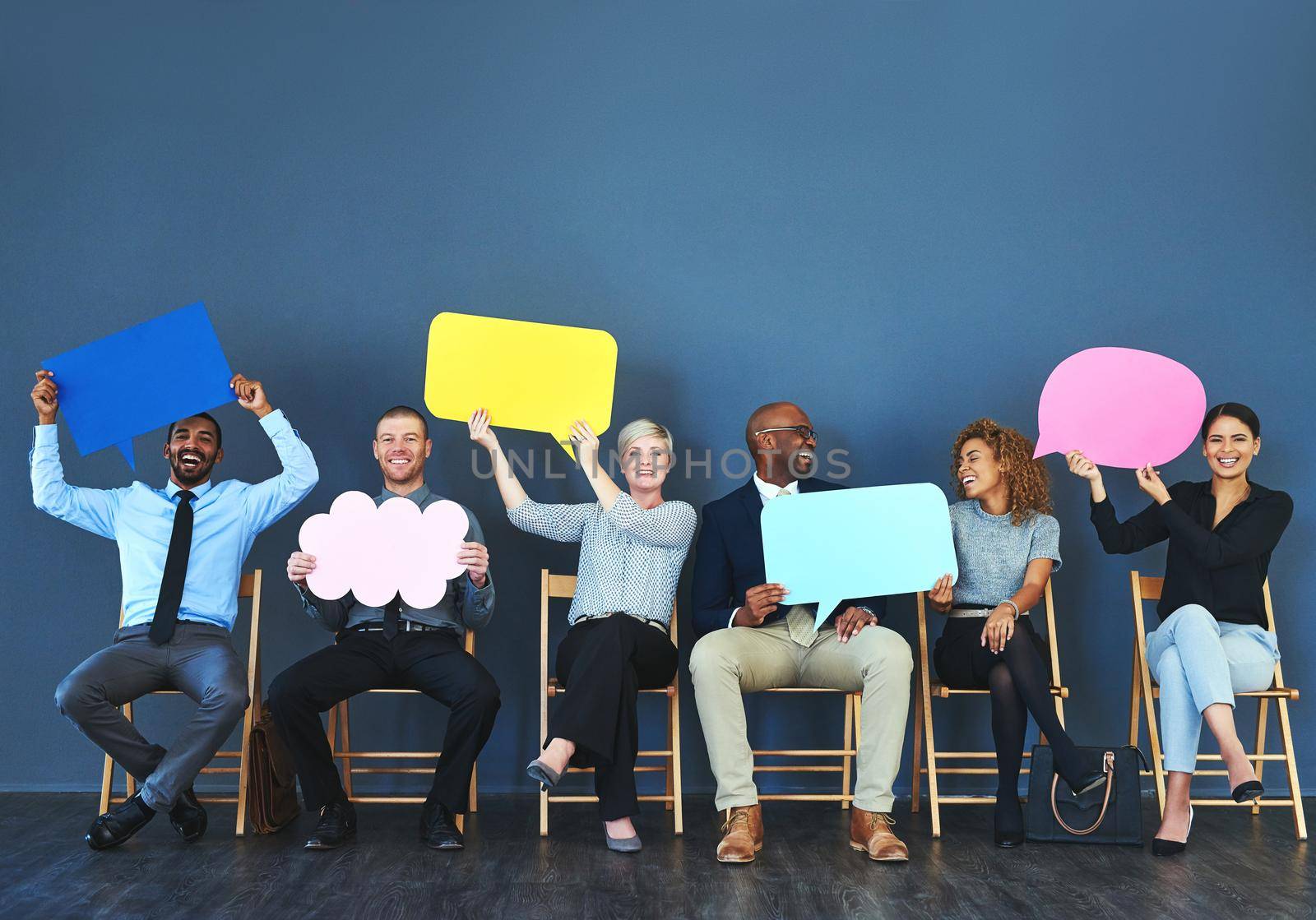 Shot of a group of people holding up speech bubbles against a blue background.