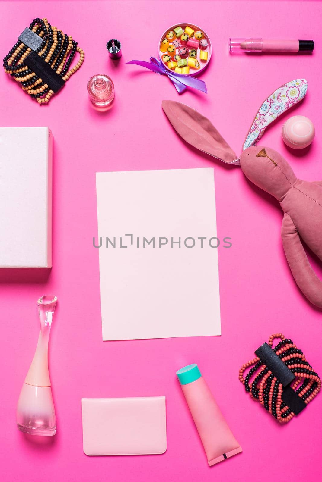 Flat lay, top view, mock up girl's accessories on a pink background. bracelet, rabbit, toy, perfume