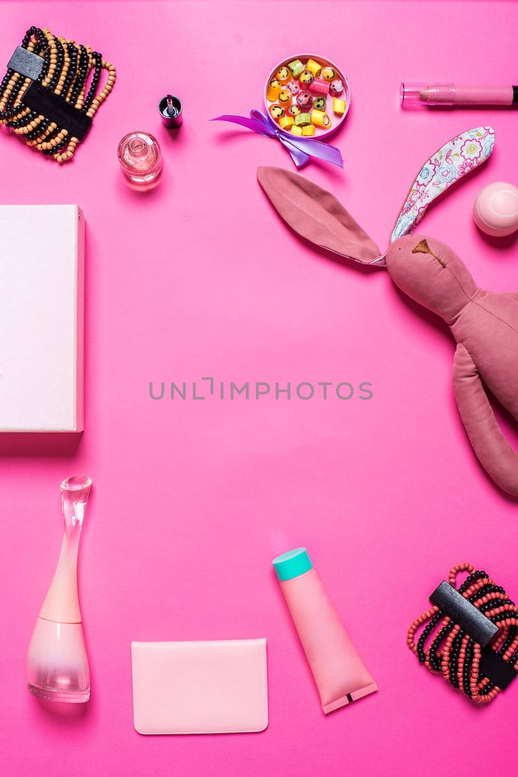 Flat lay, top view, mock up girl's accessories on a pink background. bracelet, rabbit, toy, perfume
