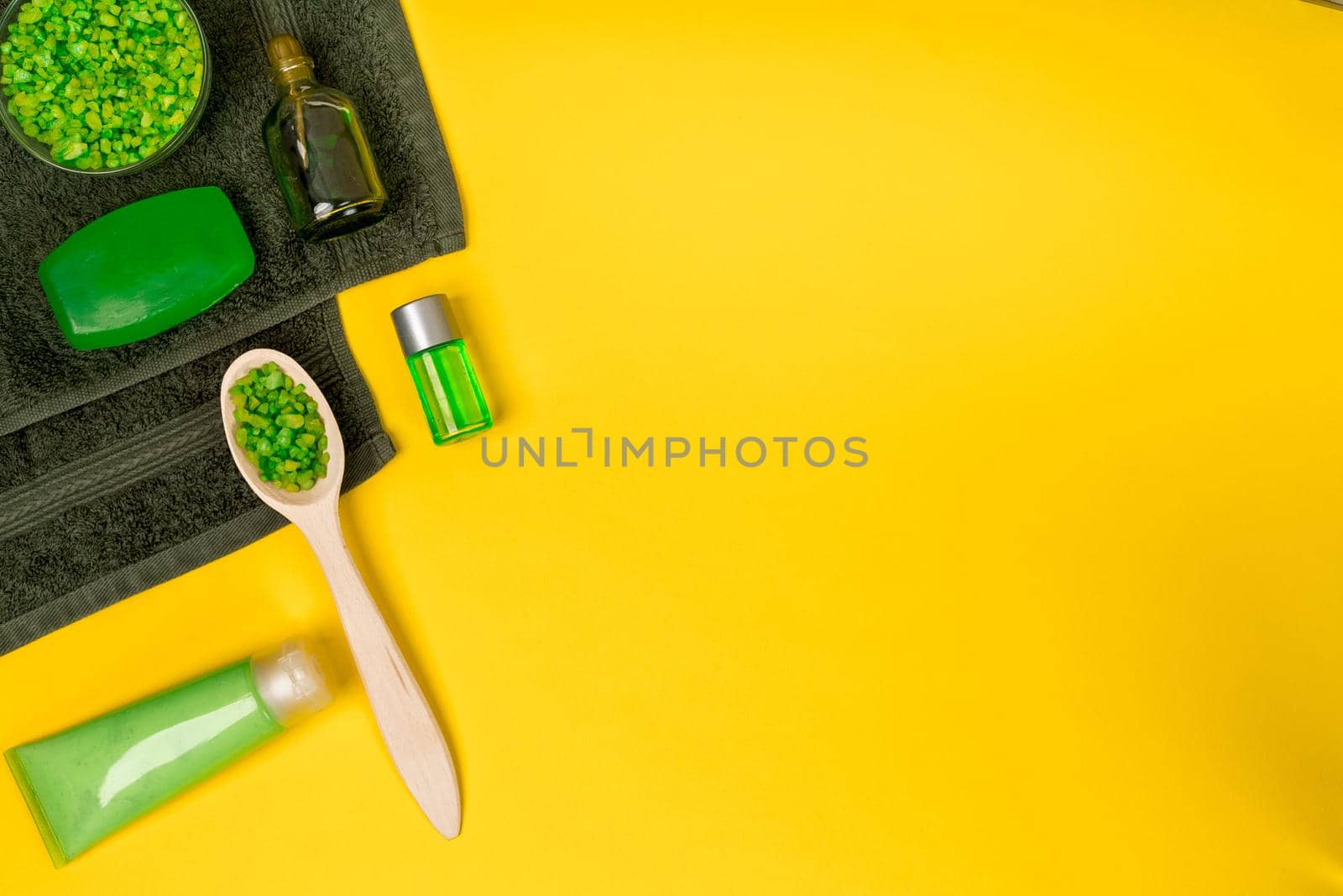 Spa set: soap, mask, oil, sea salt and towel on yellow background. Top view. Still life. Copy space
