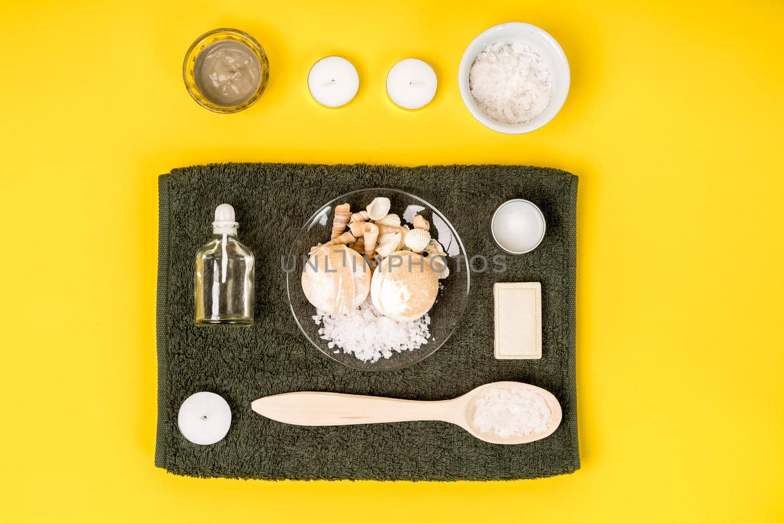 Spa set: soap, essential oil, sea salt and towel on a yellow background. Still life. Copy space