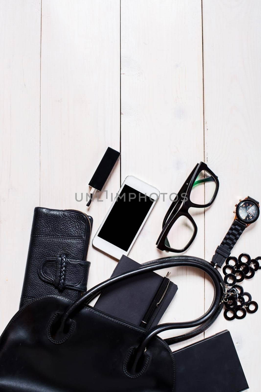 Women's accessories fell out of the black handbag on white background. by nazarovsergey