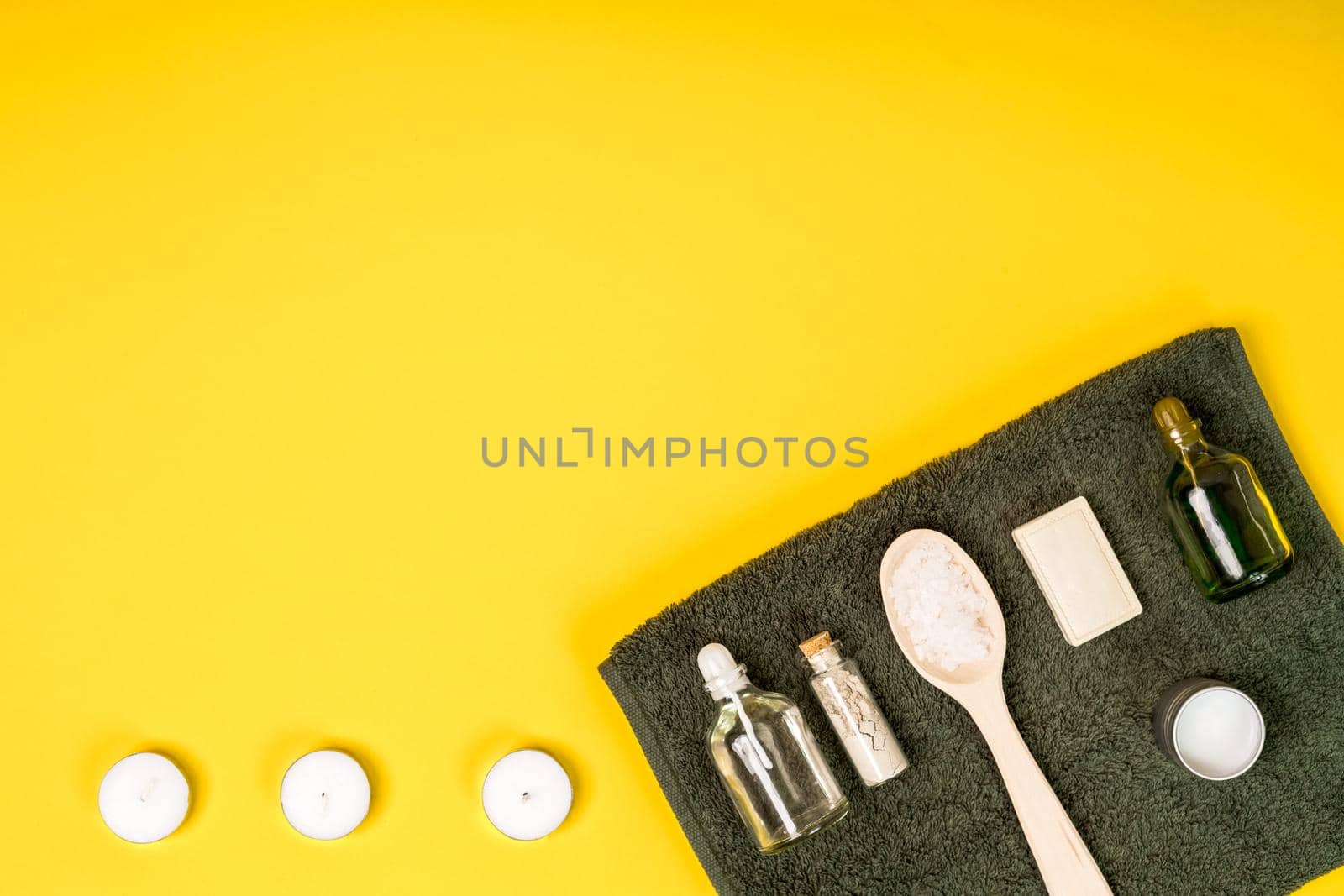 Spa set: soap, essential oil, sea salt and towel on a yellow background. Still life. Copy space