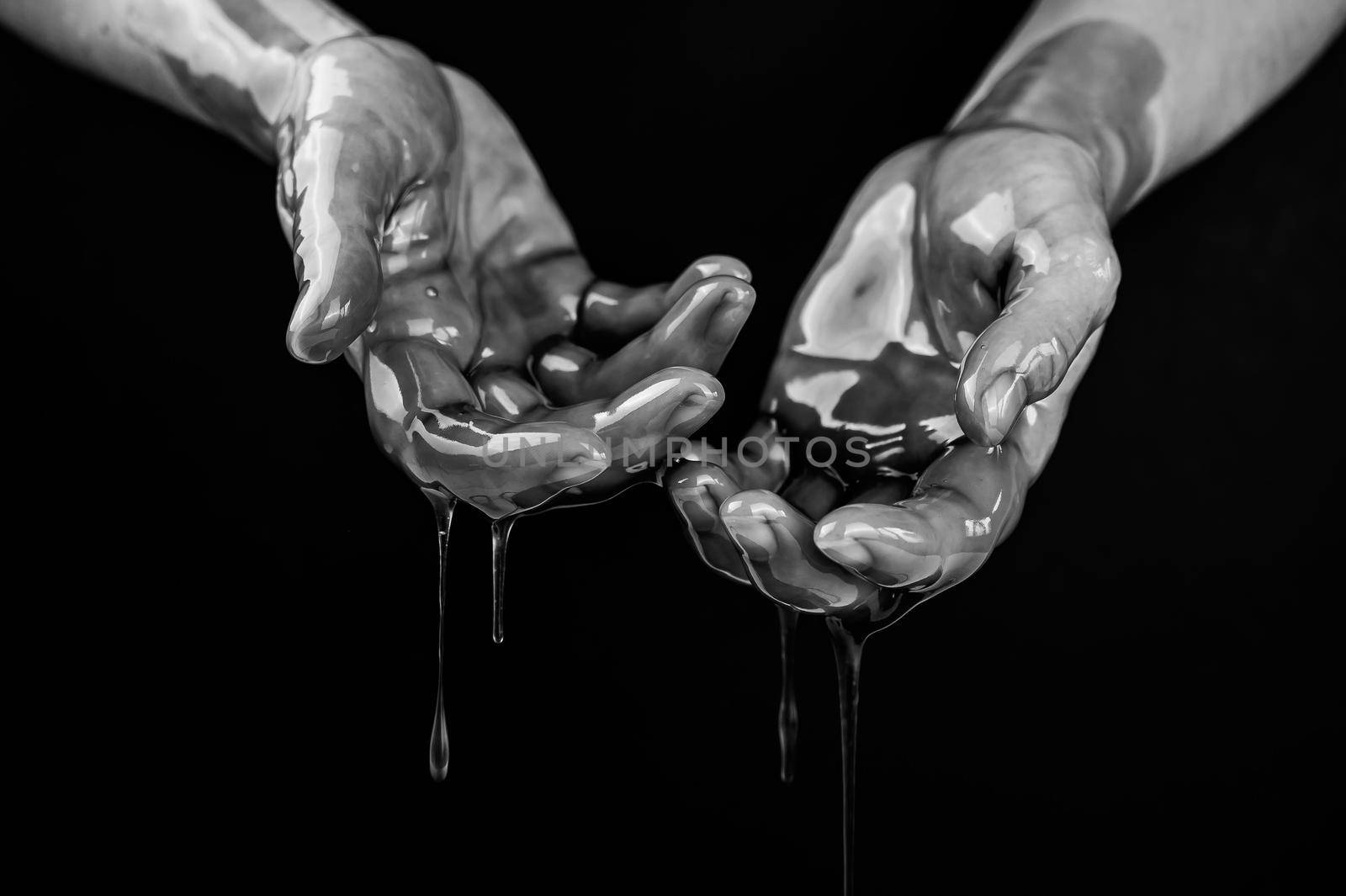 Women's hands in a viscous liquid similar to blood. Black and white photo
