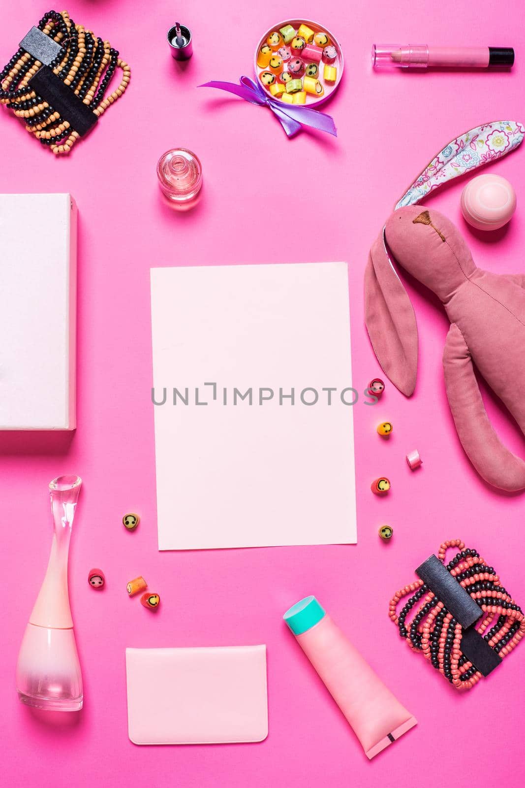 Flat lay, top view, mock up girl's accessories on a pink background. bracelet, rabbit, toy, perfume