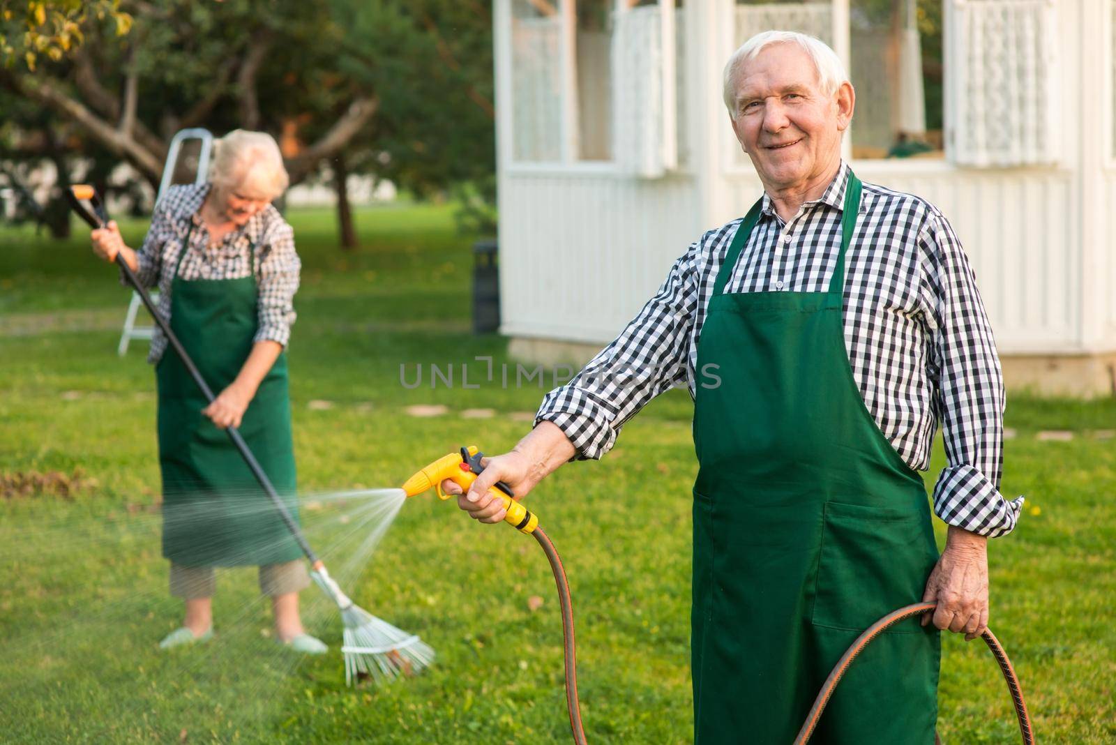 Man with garden hose smiling. by super_picture