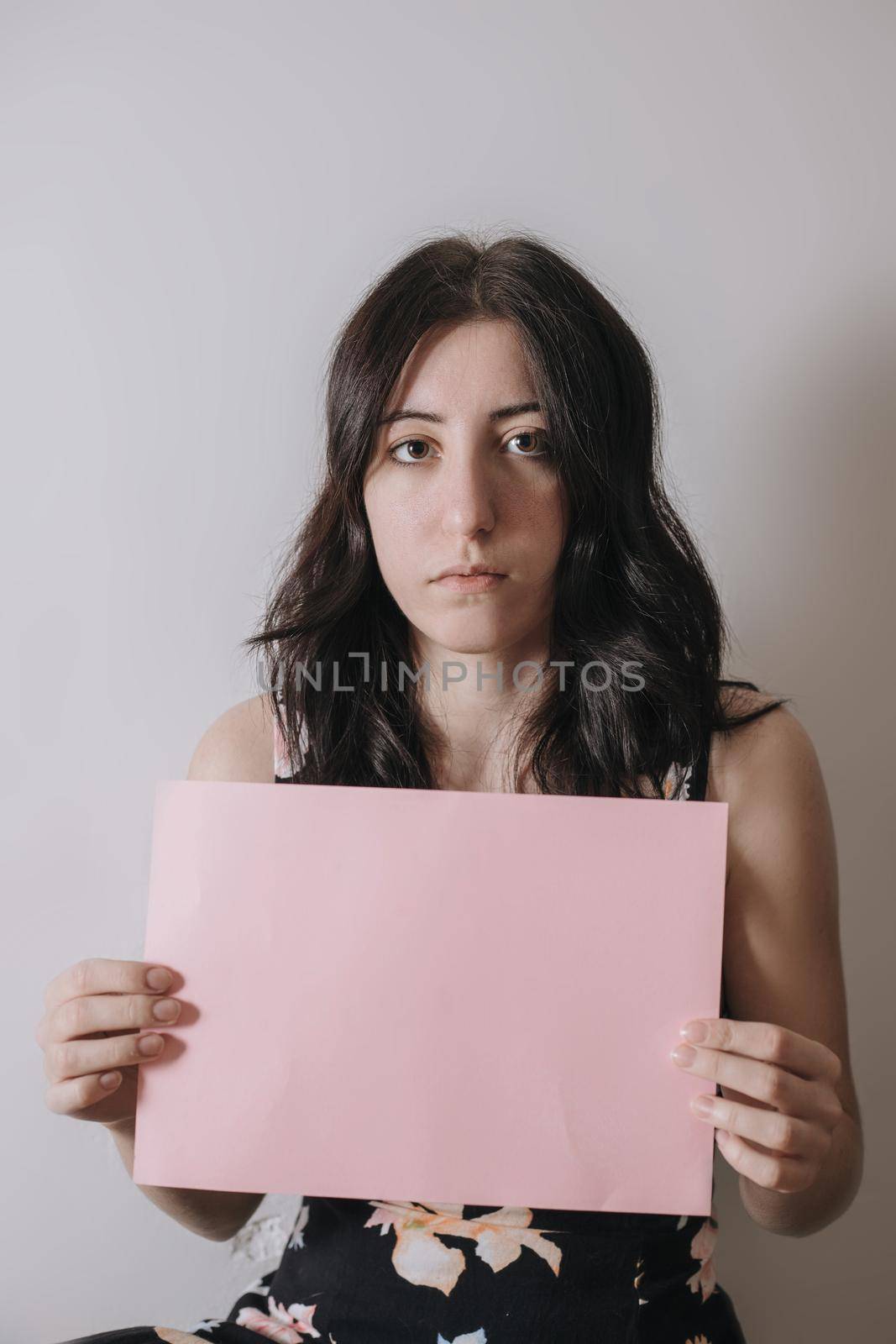 Sad young woman holding a blank banner. Woman holding blank sheet of paper for text.