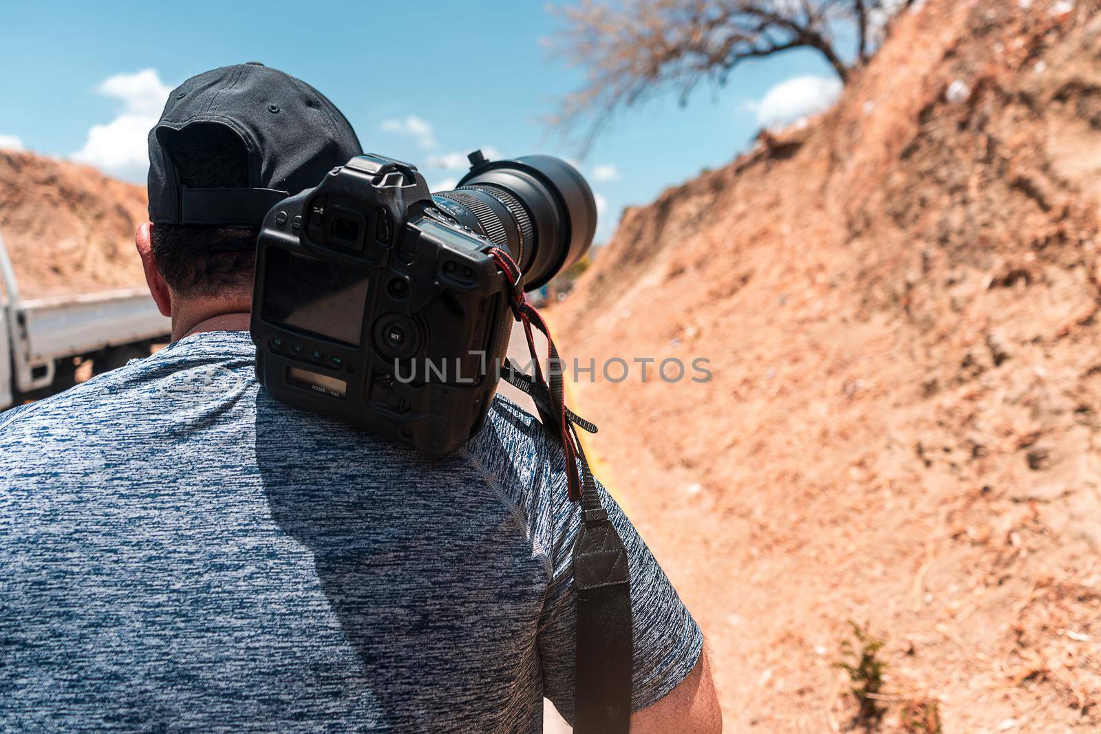 Unrecognizable photographer walking down a dirt path in search of landscape by cfalvarez