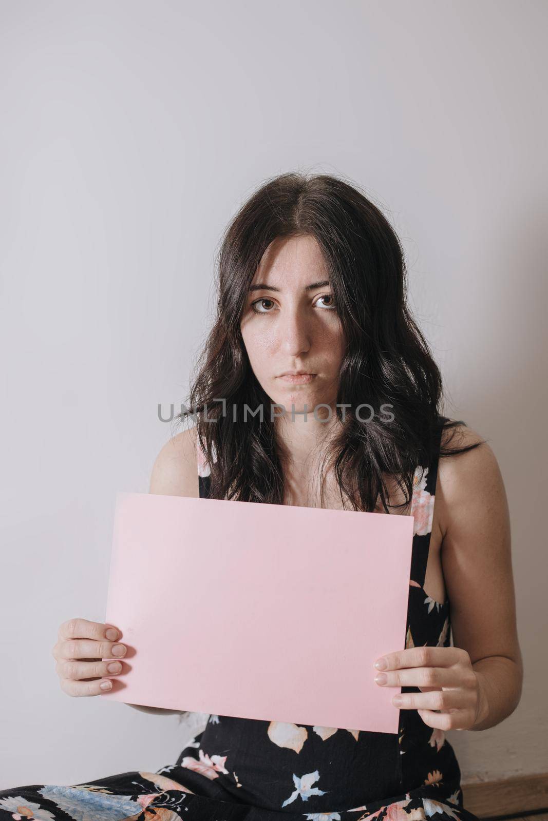 Sad young woman holding a blank banner. Woman holding blank sheet of paper for text.