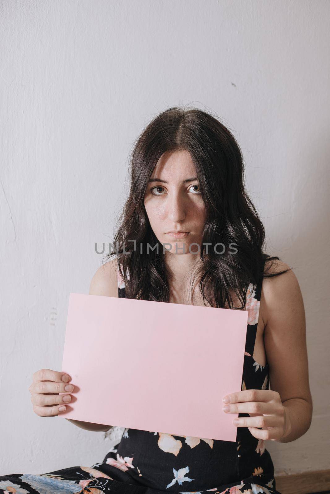 Sad young woman holding a blank banner. Woman holding blank sheet of paper for text.