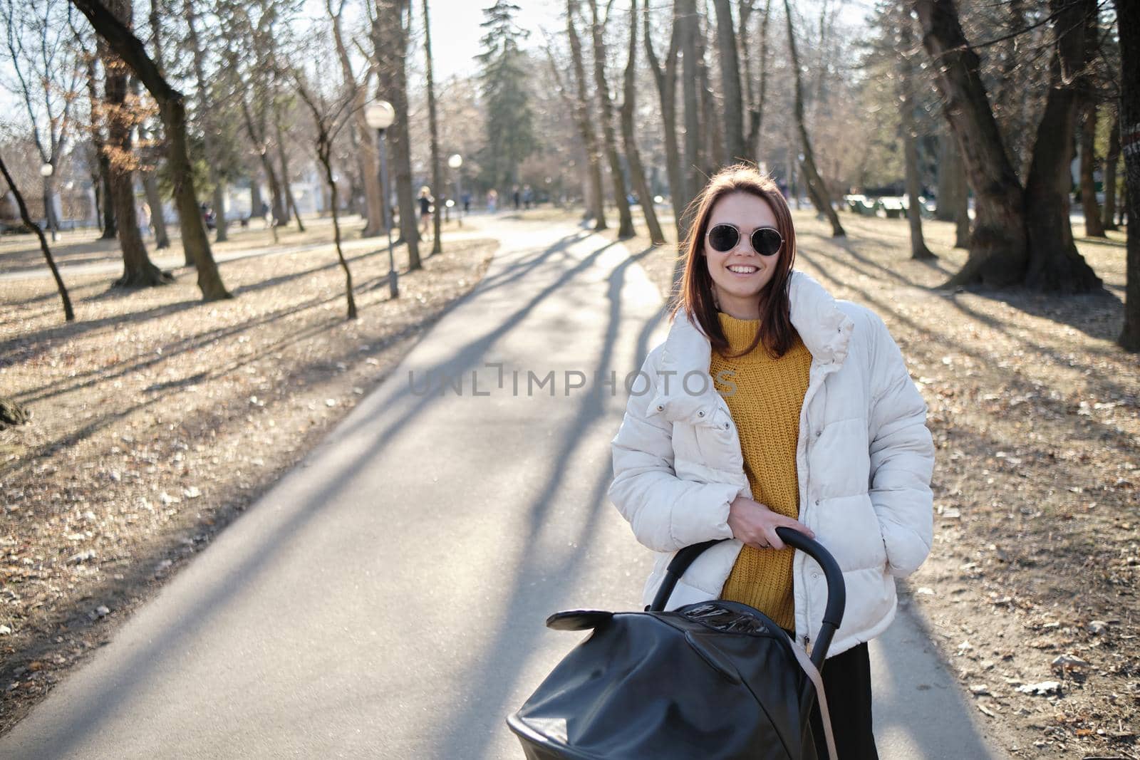 beautiful and young woman mother and baby in a stroller walking in the park