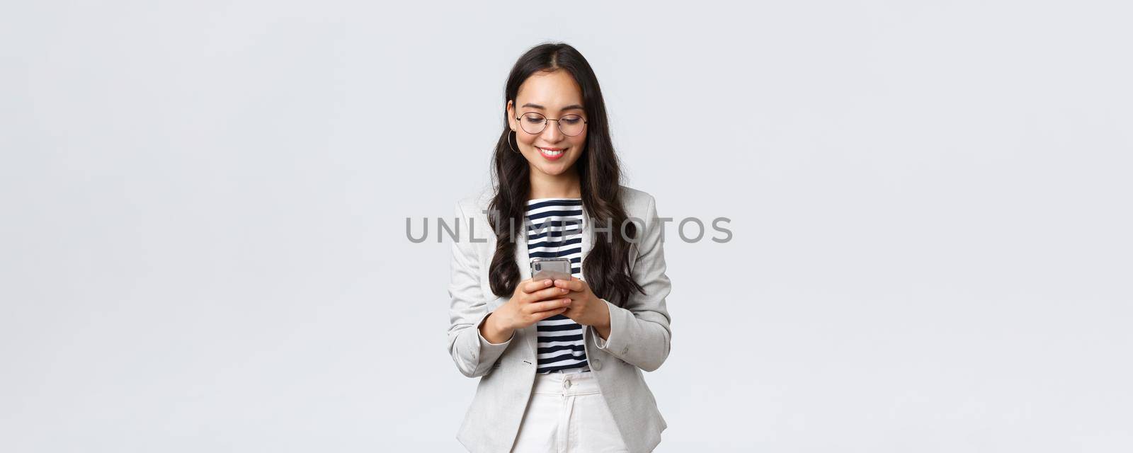 Business, finance and employment, female successful entrepreneurs concept. Businesswoman waiting for client, checking messages in smartphone, wearing glasses as looking at mobile screen.