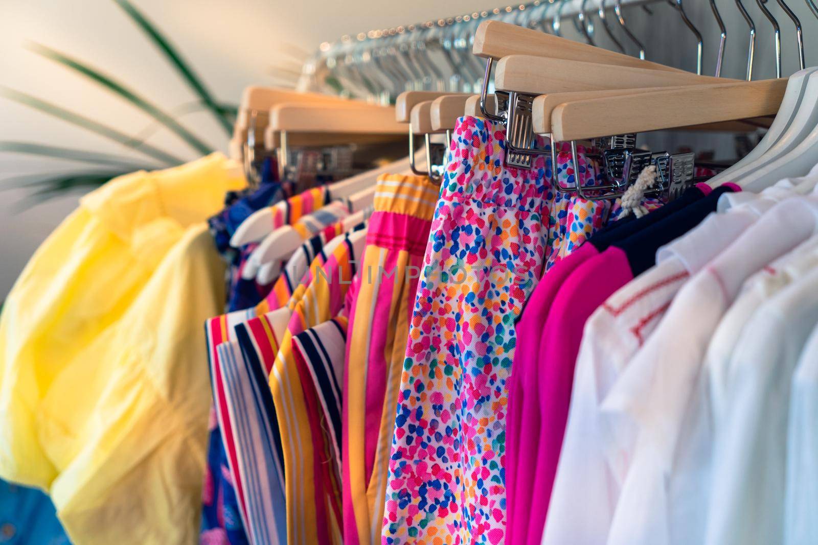 clothes rack with clothes in fashion shop. women's clothes for sale. Shopping concept by CatPhotography