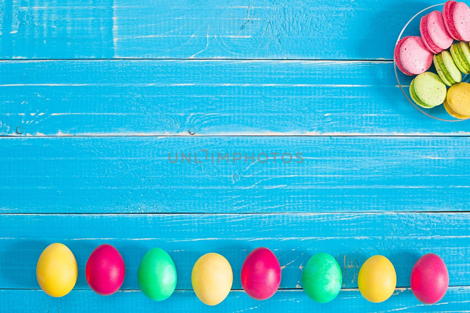 Colorful easter eggs on wooden board background with space. Top view