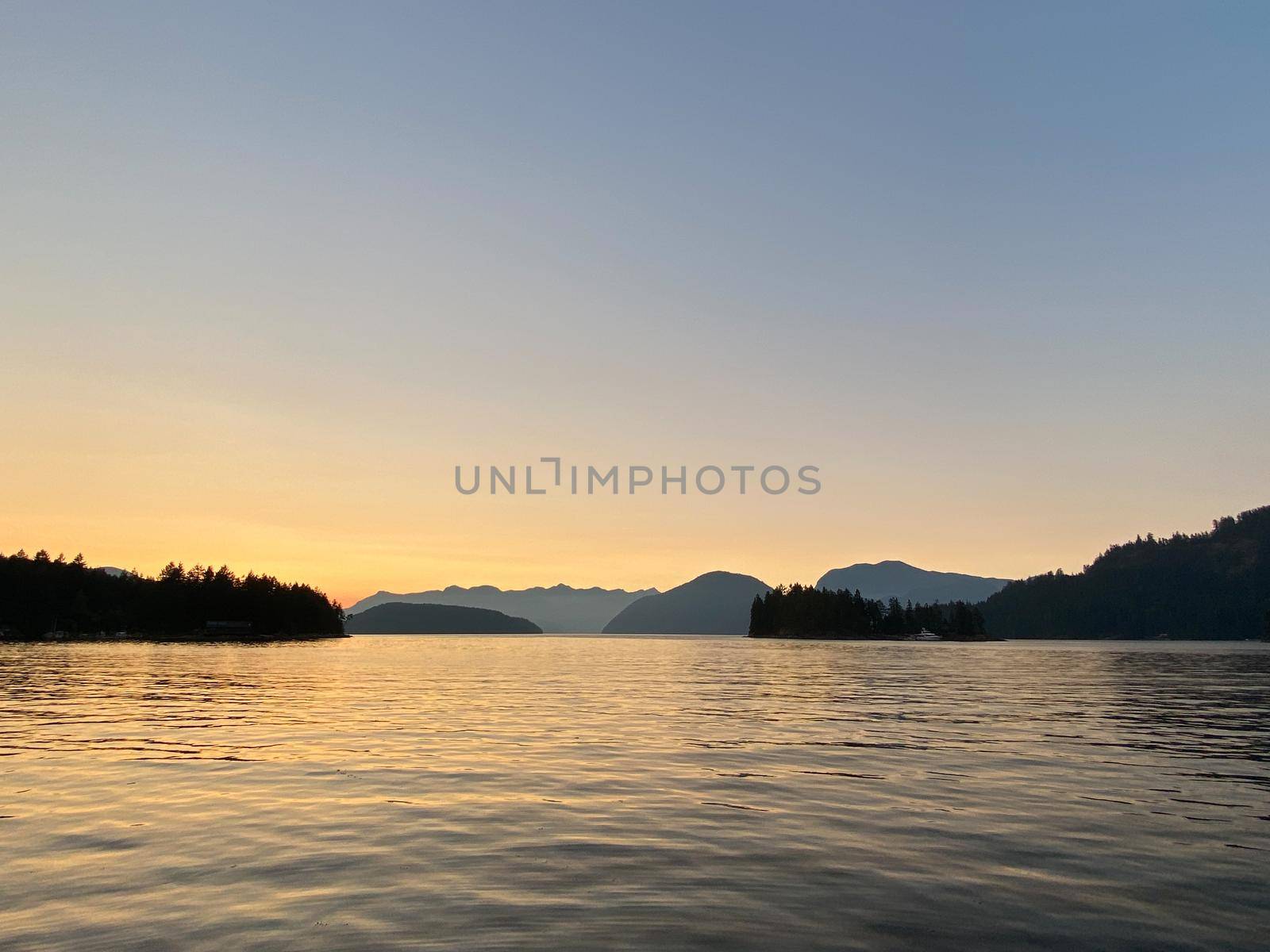 Sunset scene over mountains with reflection on water, near Thetis Island, Vancouver Island, British Columbia, Canada