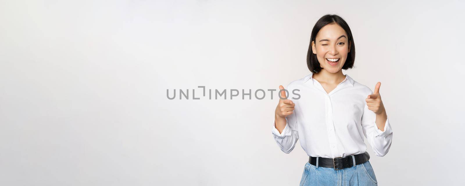 Its you congrats. Smiling attractive asian woman, businesswoman pointing fingers at camera with pleased face, complimenting, inviting you, standing over white background by Benzoix